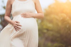 Pregnant woman touching her big belly and walking in the park relaxing in outside